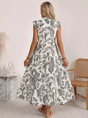 Maternity maxi dress with black and white paisley print, ruffled cap sleeves, and tiered skirt.