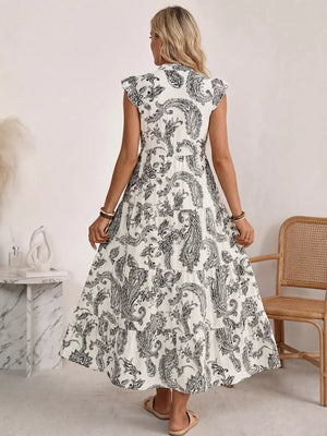 Maternity maxi dress with black and white paisley print, ruffled cap sleeves, and tiered skirt.