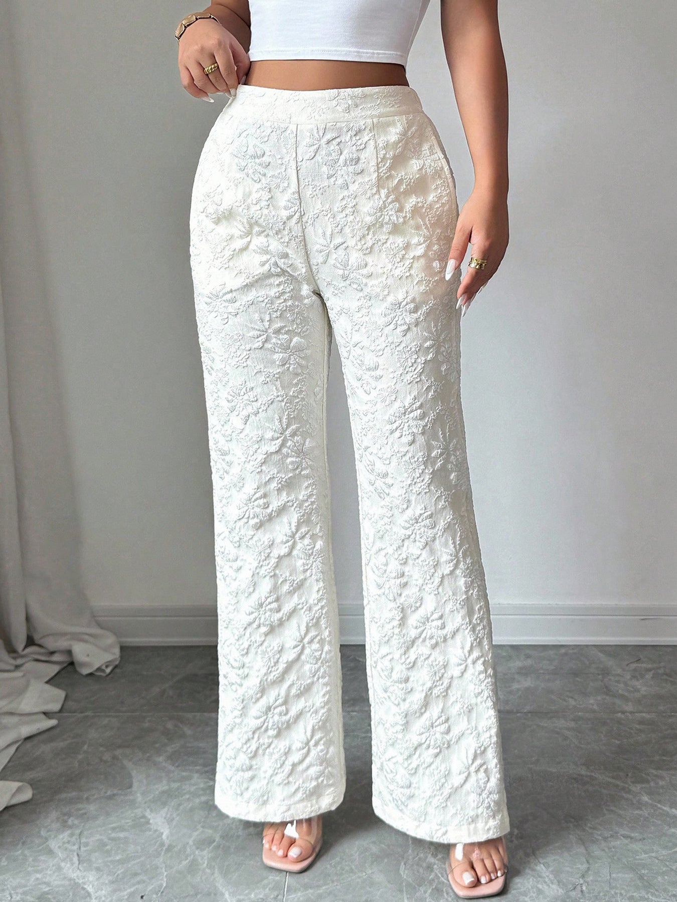 Textured white high-waist wide-leg maternity pants with pockets and a floral pattern.