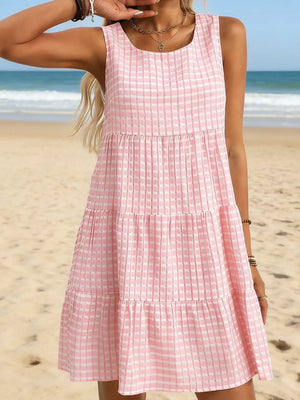 Pink tiered mini dress with a subtle plaid texture, sleeveless with a scoop neck.