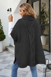 Black cable knit turtleneck poncho with side slits and a textured knit pattern.