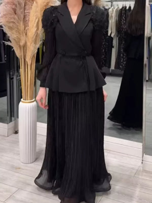 Black skirt suit with frill collar, peplum waist, and pleated maxi skirt.