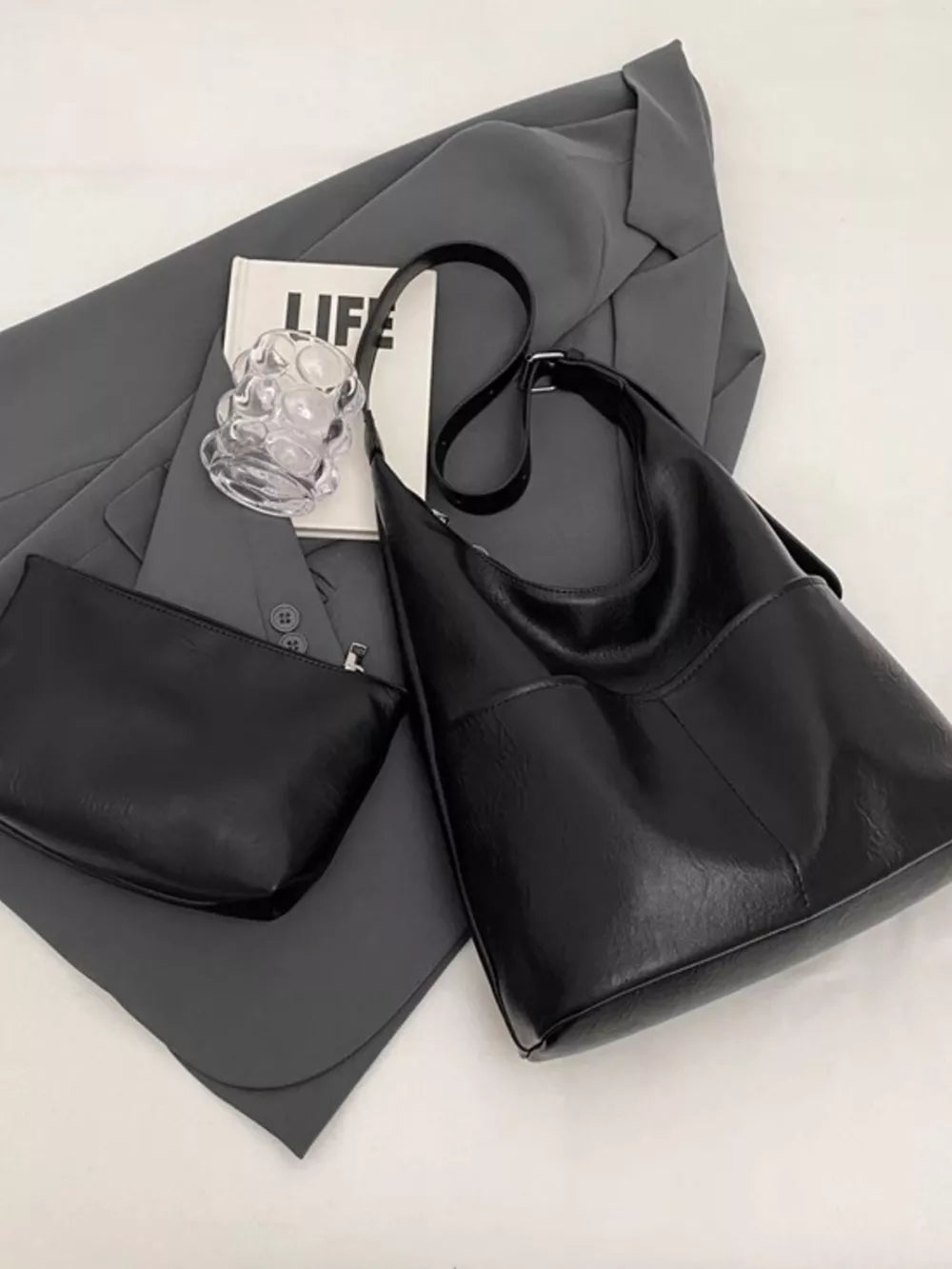 Luxurious black hobo shoulder bag with adjustable strap and matching pouch.