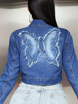 Medium wash denim crop trucker jacket with embroidered butterfly detail and frayed edges.