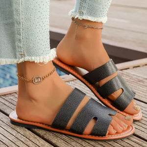 Chic black two-strap open-toe sandals with textured straps and tan soles.