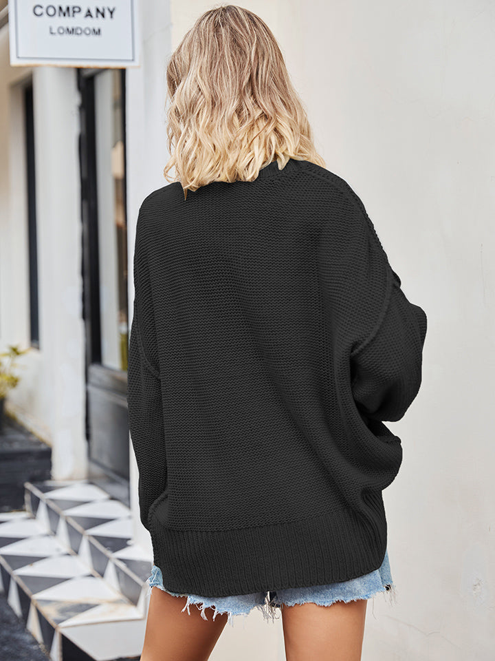 Oversized black knit V-neck sweater with ribbed hem and cuffs, styled with denim shorts.