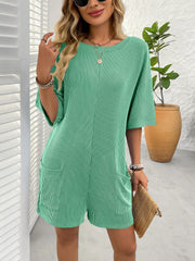 Green ribbed knit romper with short sleeves and pockets, styled with necklaces and bracelets.