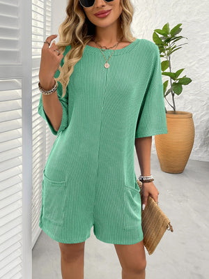 Green ribbed knit romper with short sleeves and pockets, styled with necklaces and bracelets.