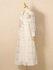 White lace midi dress with button placket, collared neckline, and floral brooch detail.