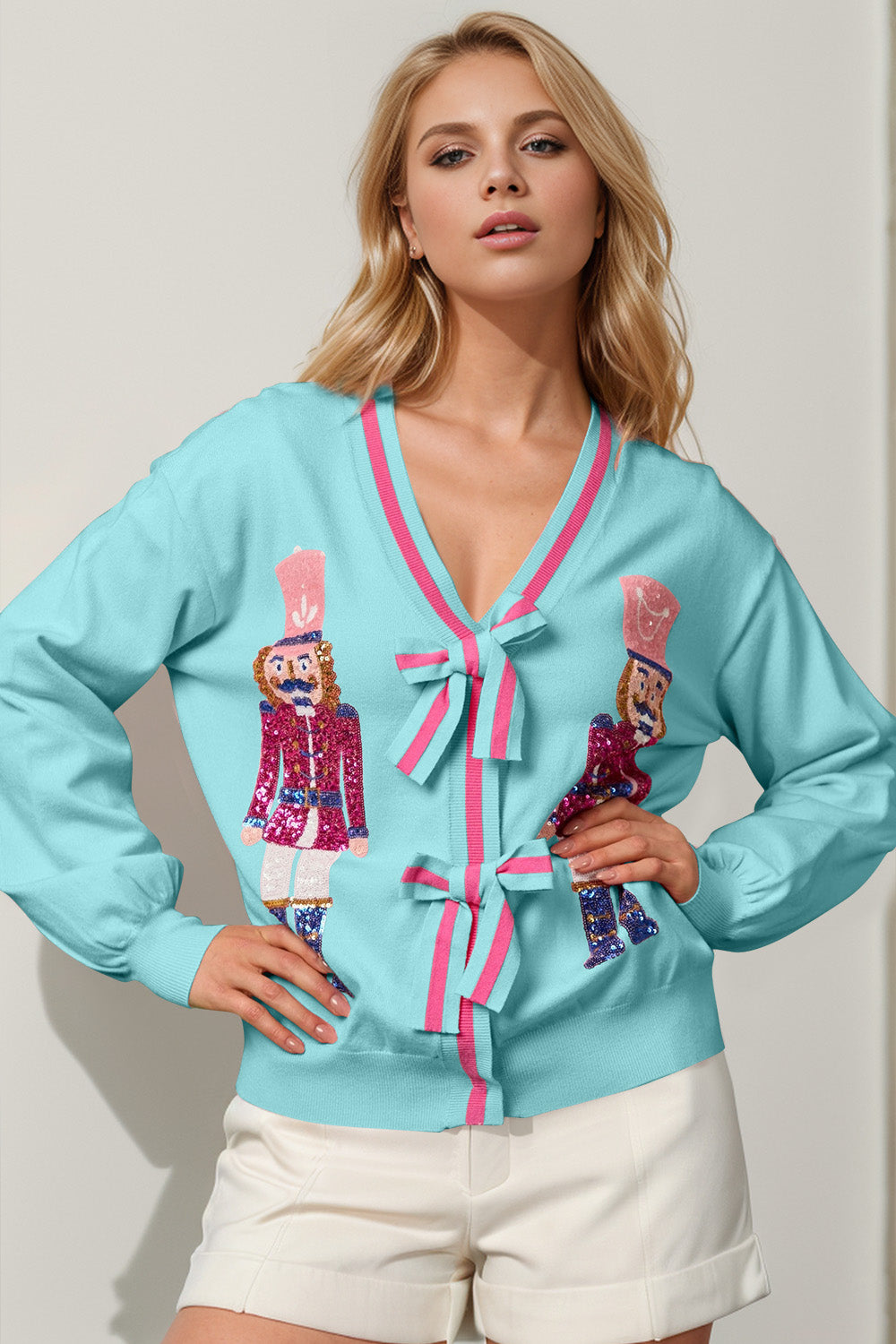 Cerulean acrylic cardigan with nutcracker embellishments and pink trim bows.