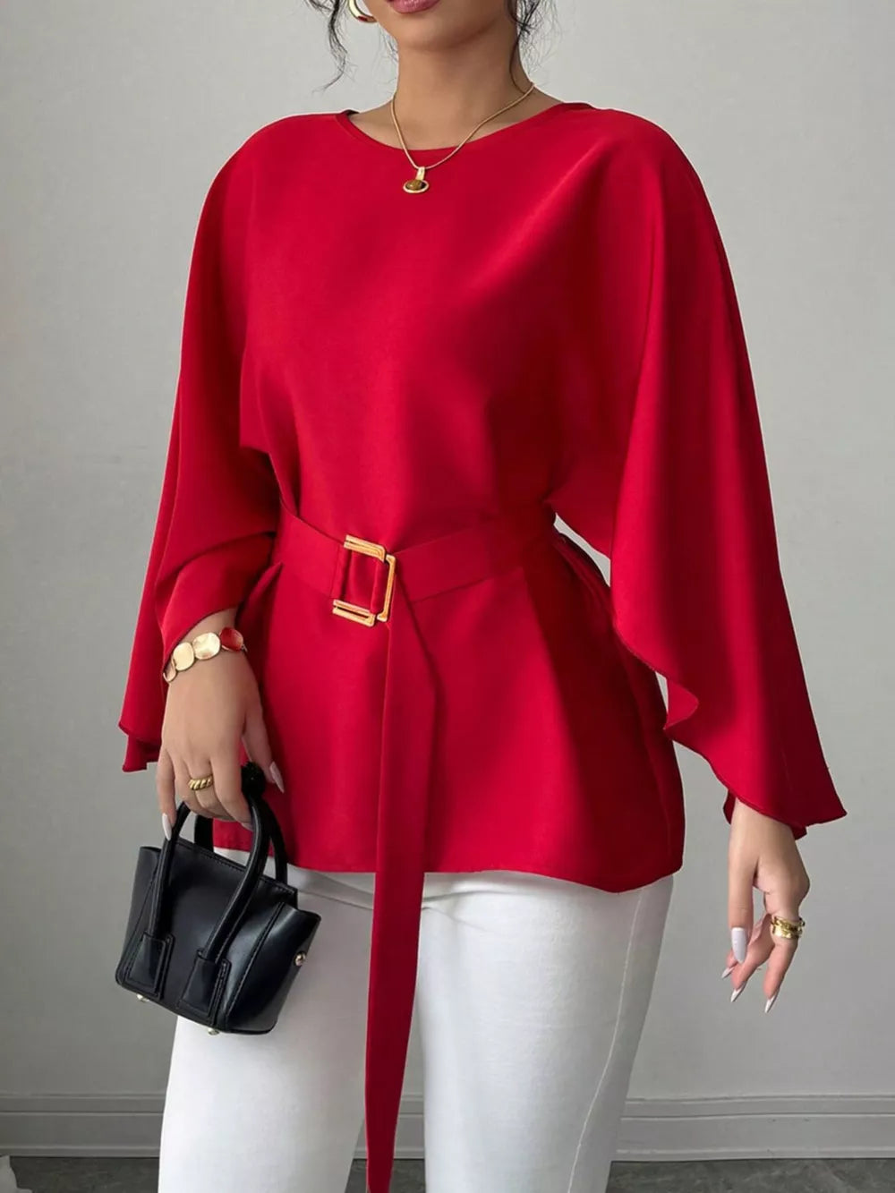 Red belted blouse with batwing sleeves and gold buckle detail.