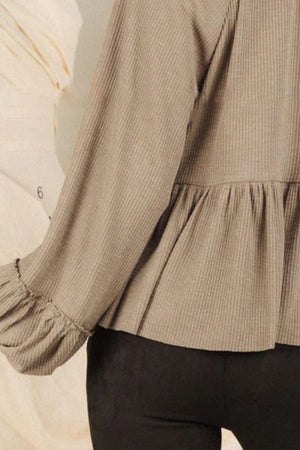 Tan ribbed peplum blouse with ruffled cuffs and long sleeves.