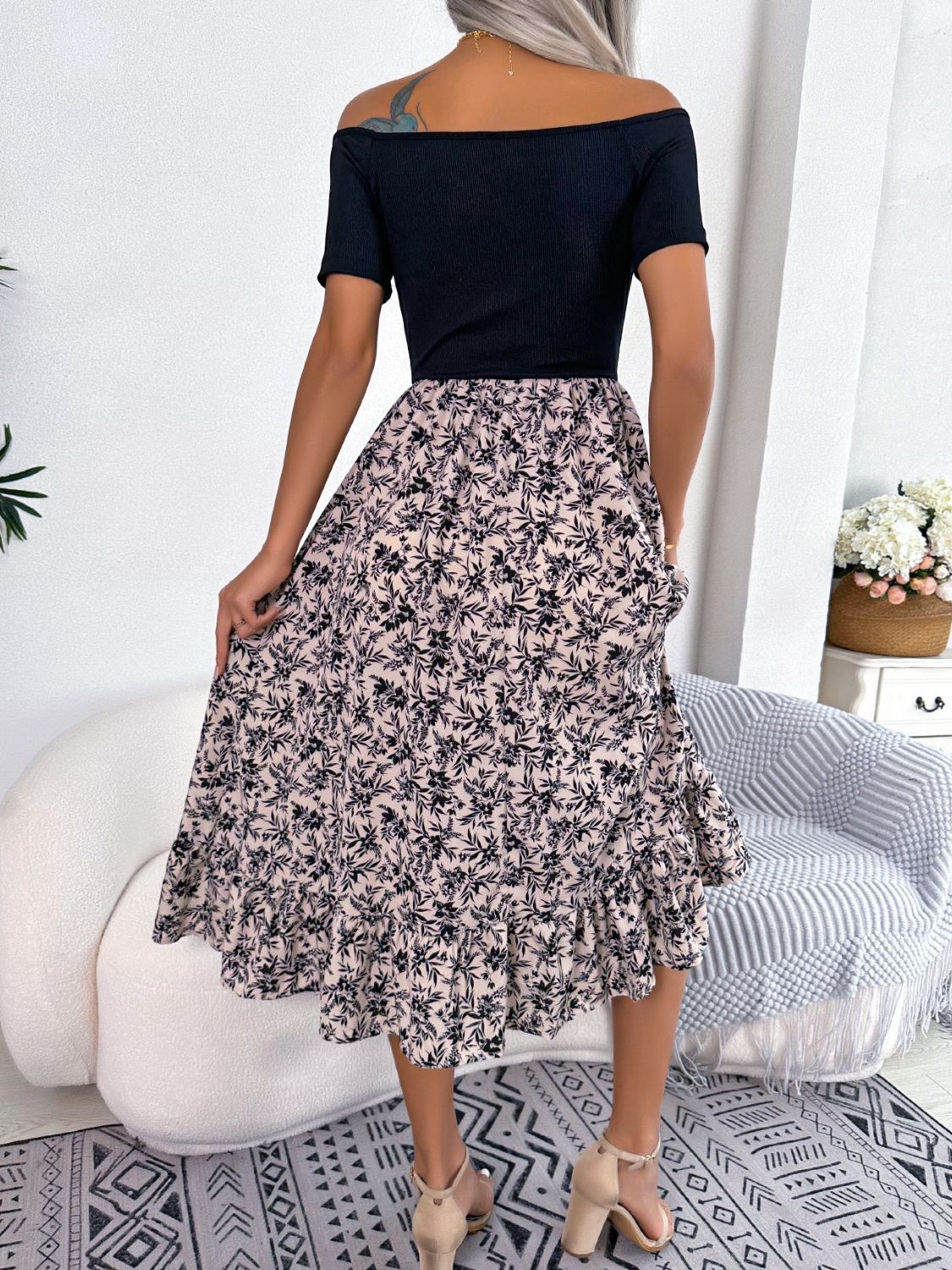 Floral off-shoulder midi dress in black with a light floral print skirt and ruffled hem.