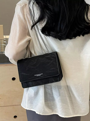 Black crumpled texture mini shoulder bag with chain strap and flap closure.