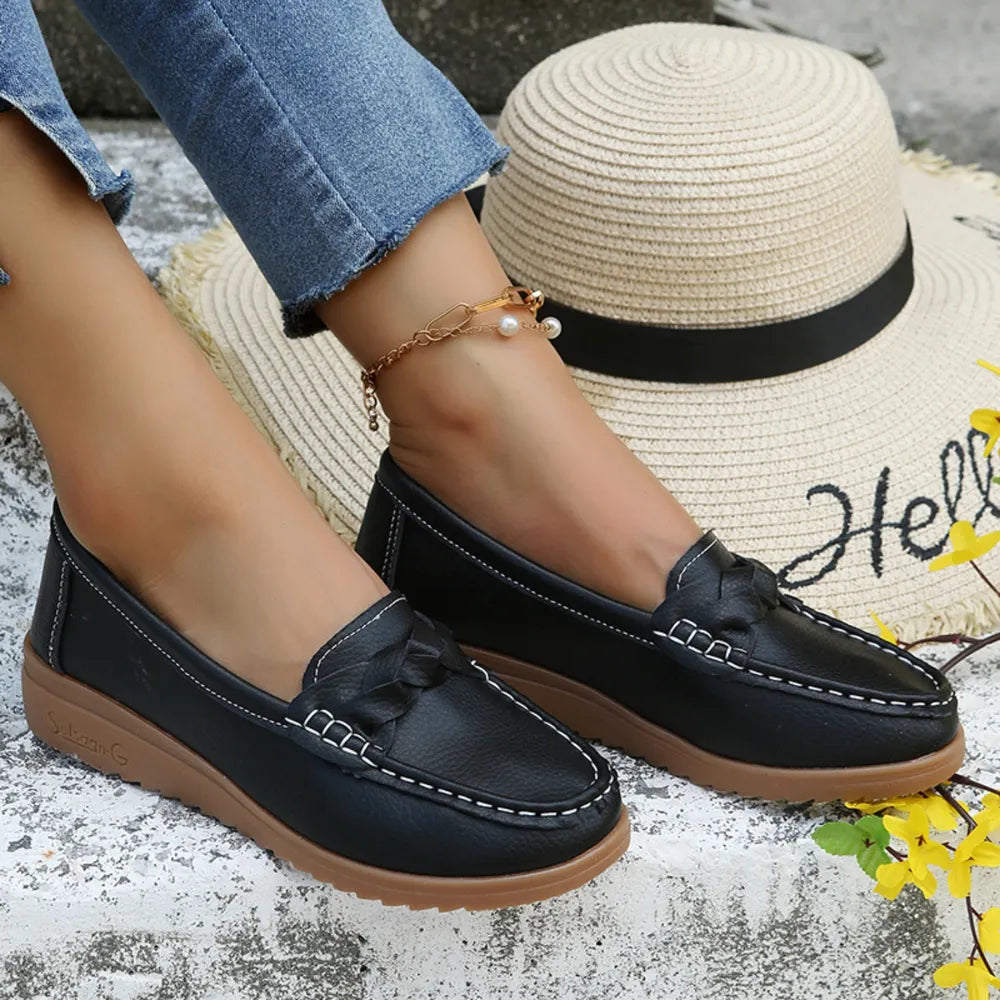 Black leather loafers with braided detail and white stitching, casual flat shoes.