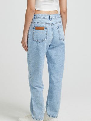 Light wash denim jeans with high rise and buttoned closure, featuring a brown leather patch detail on the back pocket.