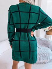 Geometric grid knit mini dress in dark green with black lines, long sleeves, and a black elastic waistband.