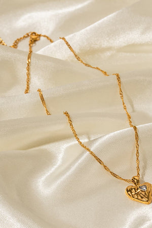 Gold textured heart pendant necklace with a clear stone detail on a delicate chain.