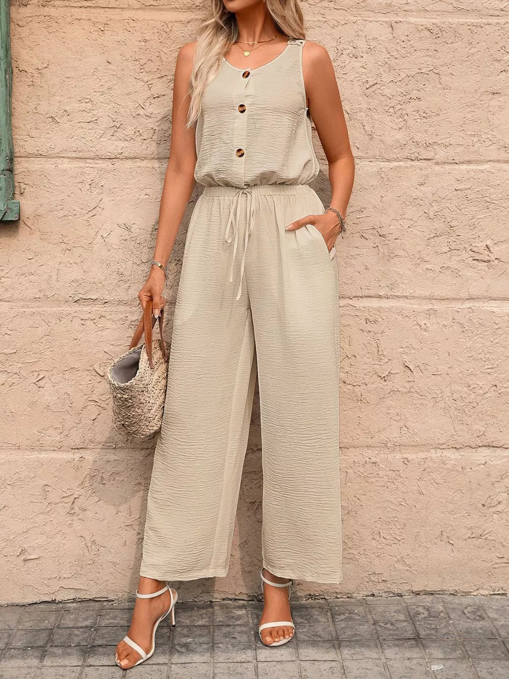 Khaki wide-leg romper with button detail, drawstring waist, and textured fabric.