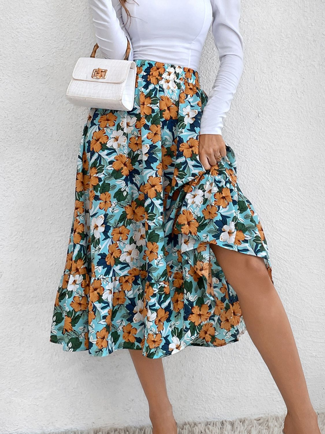 Tiered midi skirt with a floral print in blue, orange, and white, featuring a ruffled hem and a side slit.