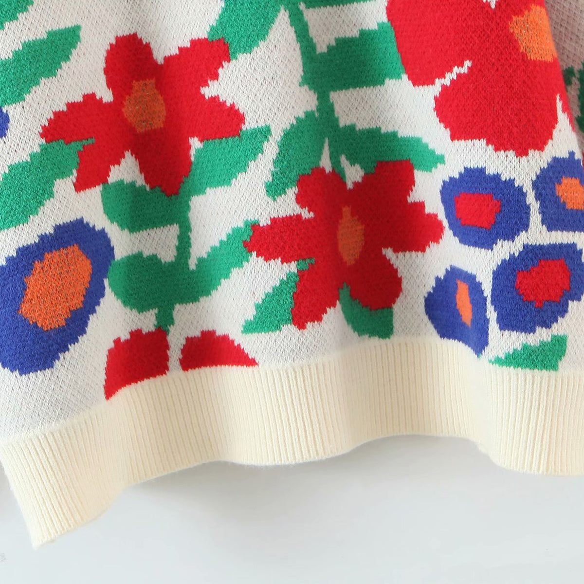 White acrylic crewneck knit sweater with a colorful floral intarsia pattern and ribbed hem.