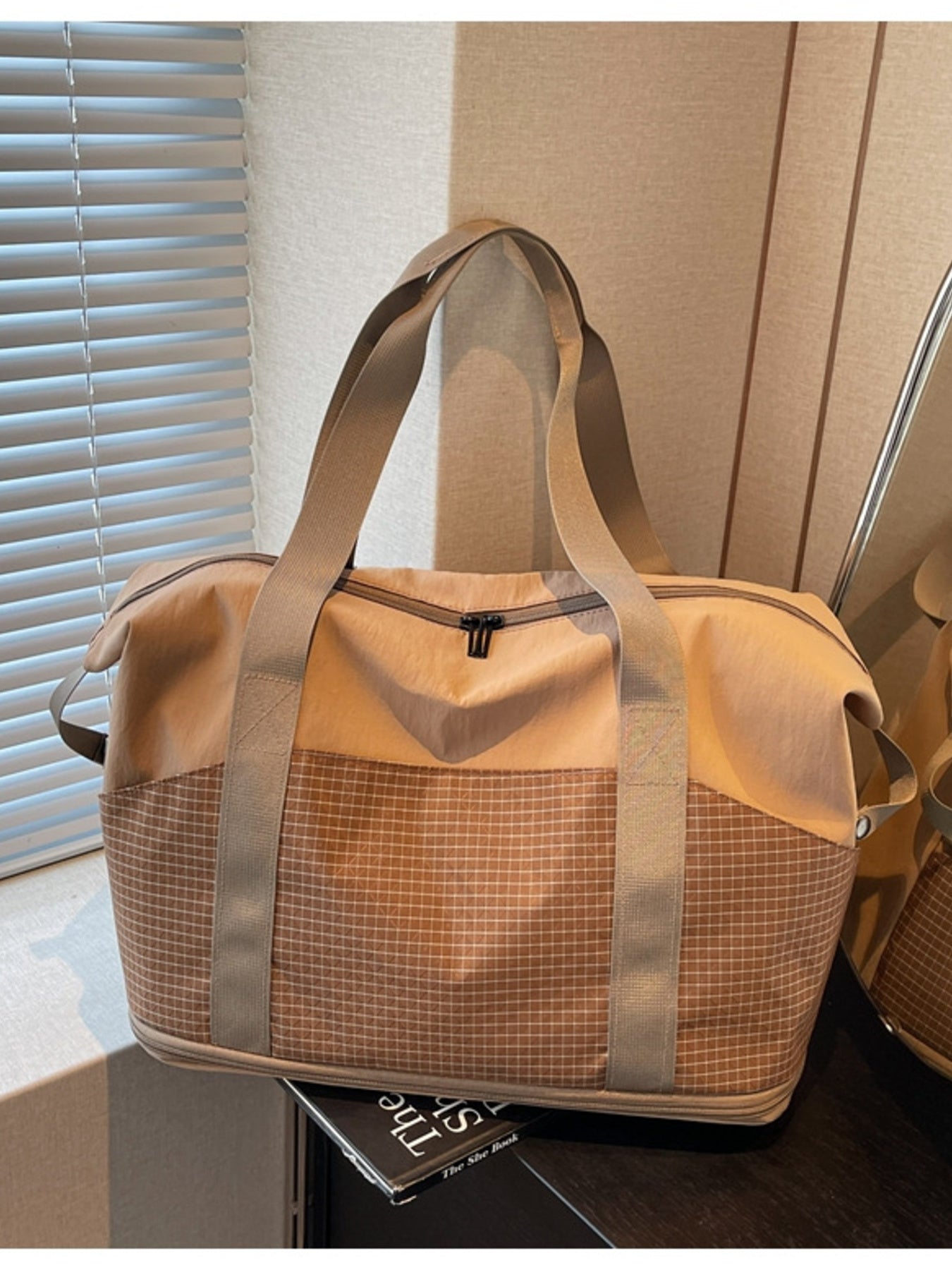 Spacious nylon travel duffel bag in tan with grid pattern lower panel and tan straps.
