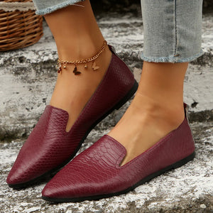 Burgundy textured pointed-toe slip-on loafers with a subtle snake print pattern.
