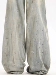 Light vintage wash wide-leg denim trousers with distressed details and paint splatters.