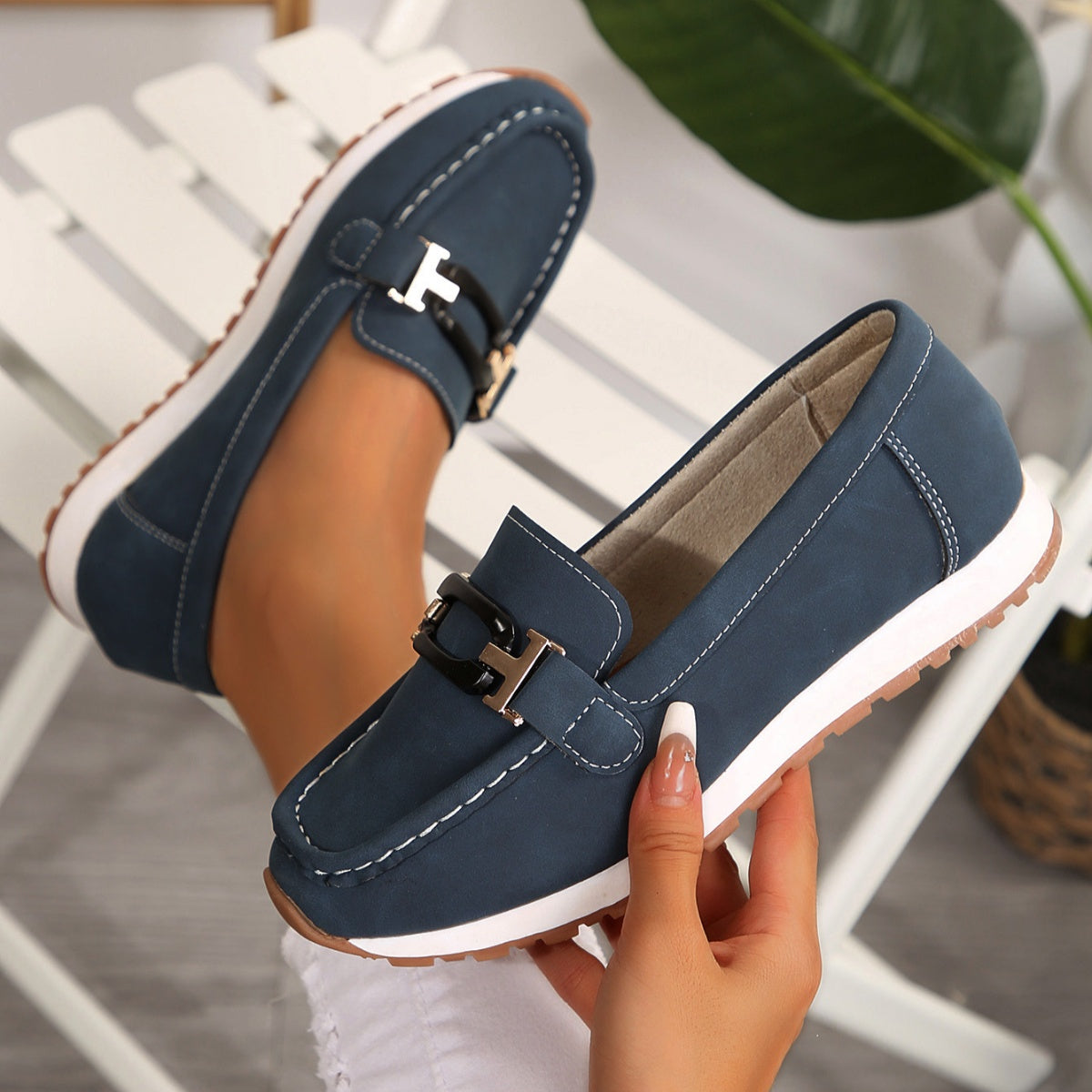 Dark blue slip-on loafers with gold and black buckle detail and contrast stitching.