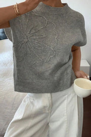Gray knit top with embroidered bloom detail, short sleeves, and mock neck.