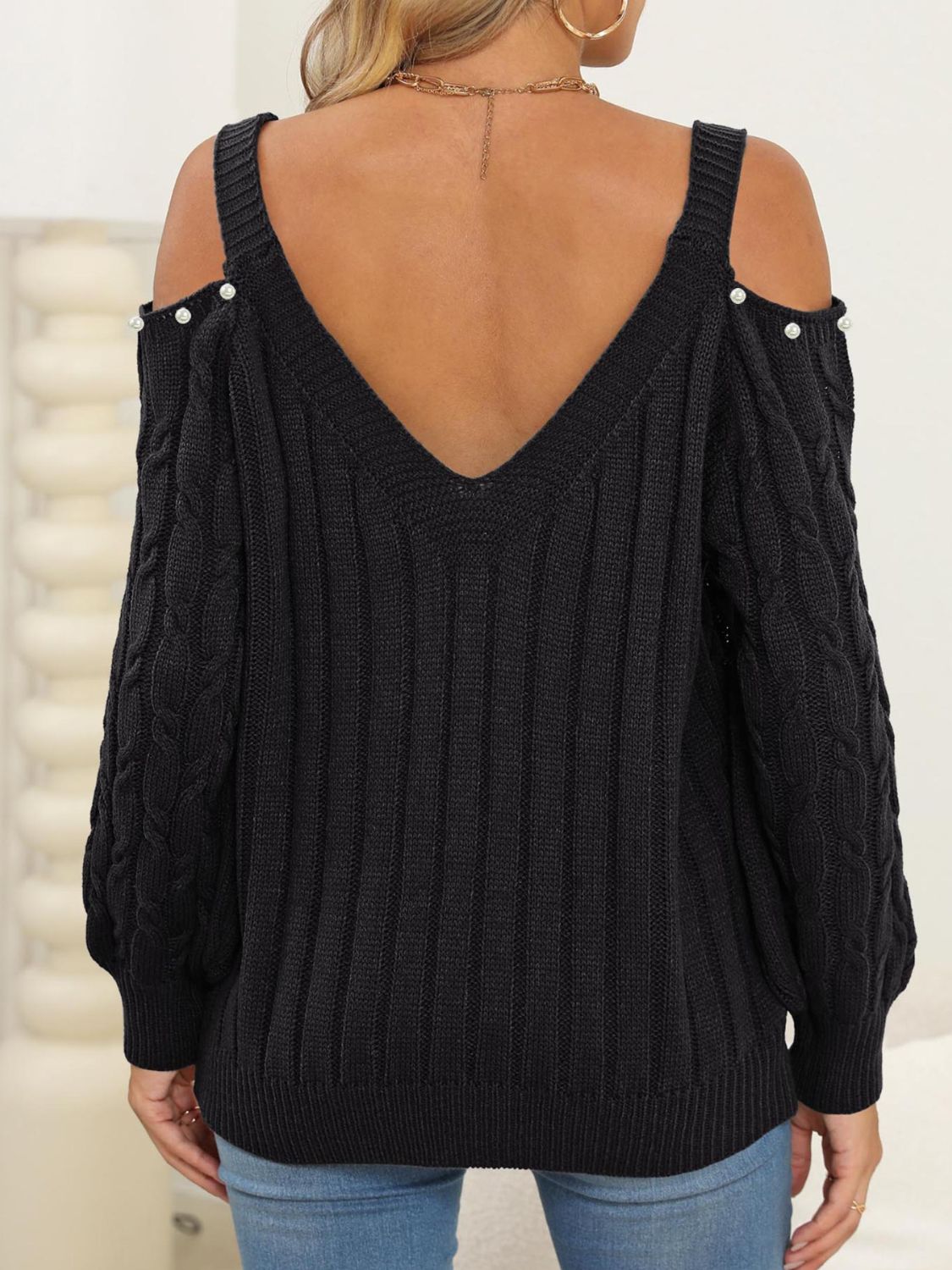 Black cable knit sweater with cold shoulder detail and pearl buttons, V-neck.