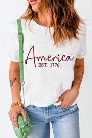 White t-shirt with red "America EST. 1776" graphic, short sleeves, crew neck.