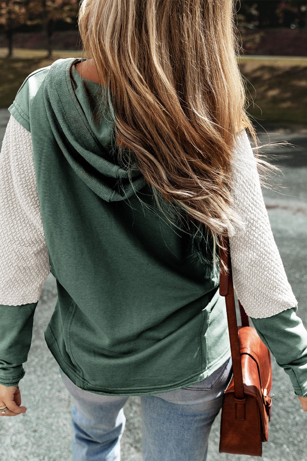 Sage green hoodie with textured white sleeves and a drawstring hood.
