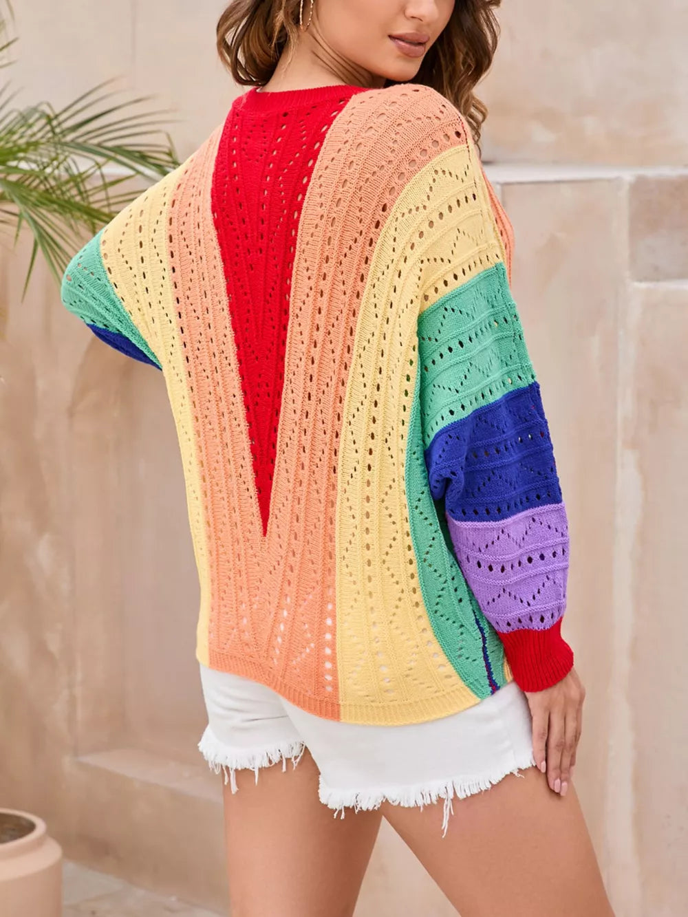 Vibrant color-blocked openwork knit sweater with rainbow stripes and a V-neck detail.