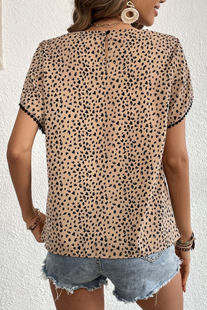 Leopard print blouse with pom-trim sleeves and a keyhole back detail.
