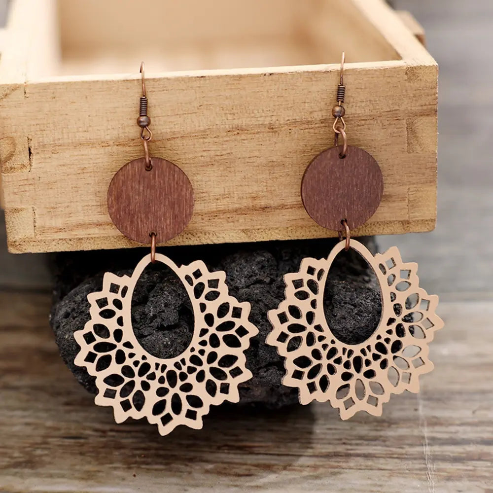 Floral laser-cut wooden drop earrings with tan wood circles and intricate lace-like cutouts.