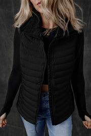 Black quilted puffer vest with fleece collar and zip front, worn over a black top.