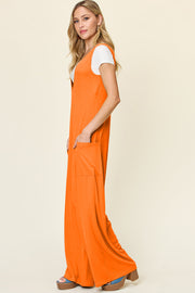 Tangerine wide-leg jumpsuit with deep V-neck and front pockets, styled over a white tee.