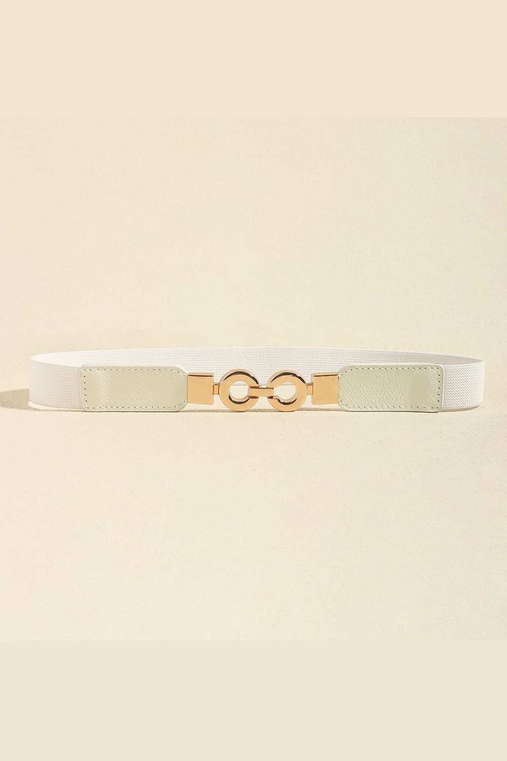 White elastic belt with gold interlocking circle buckle and faux leather ends