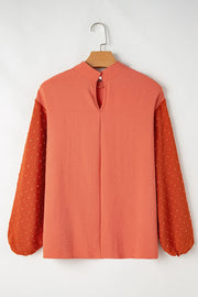Orange blouson top with mock neck and Swiss dot sleeves