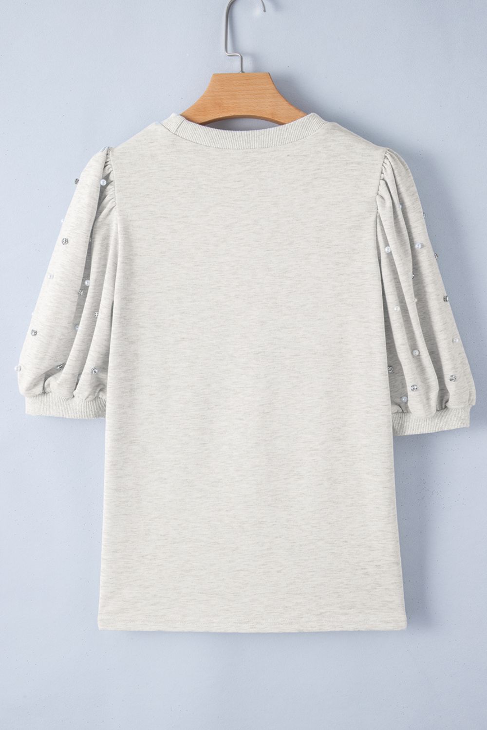 Light gray sweatshirt with embellished puff sleeves and pearl details.