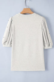 Light gray sweatshirt with embellished puff sleeves and pearl details.