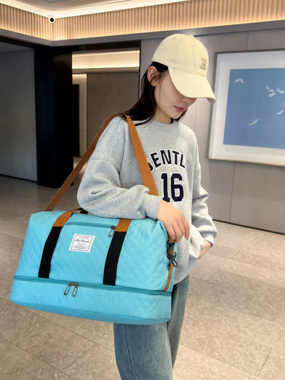 Luxurious quilted travel duffel bag in Lake Blue with brown straps and double zippers.