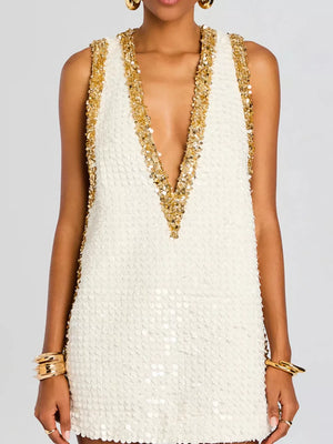 Glistening sequin mini dress in white with gold V-neck trim and gold jewelry.