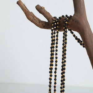 Black onyx and gold bead necklace with alternating beads on display.