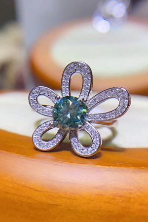 Teal moissanite ring with diamond accents in a flower halo design.