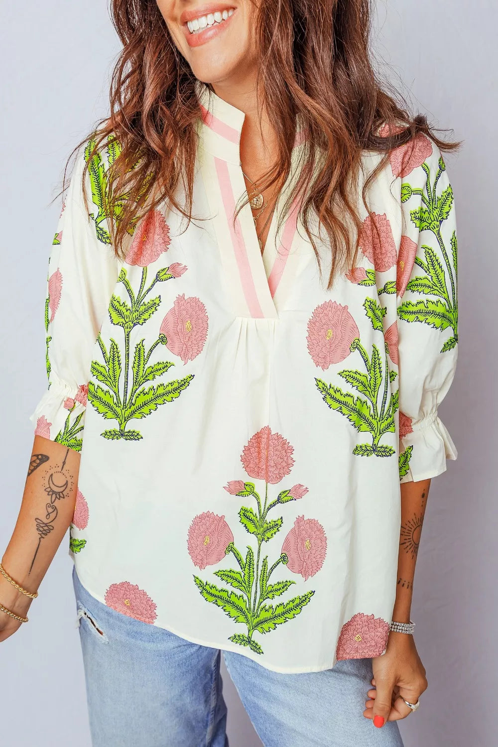 Cream cotton blouse with pink floral print, ruffled sleeves, and notched neckline.