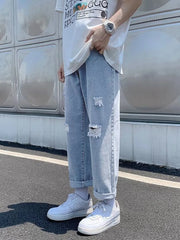 Distressed relaxed fit blue jeans with cuffed hem and ripped details.