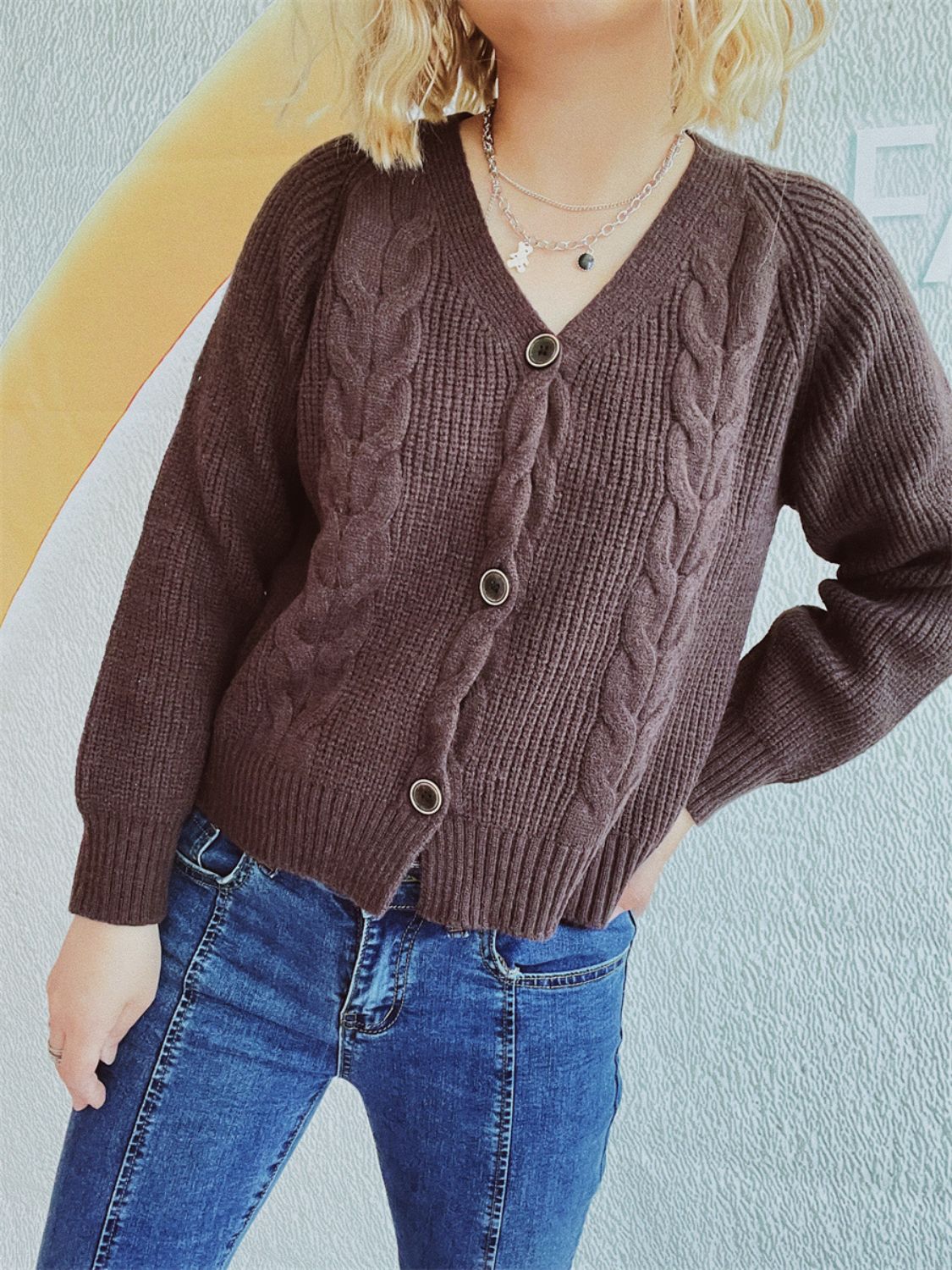 Brown cable knit raglan cardigan with V-neck and button front.