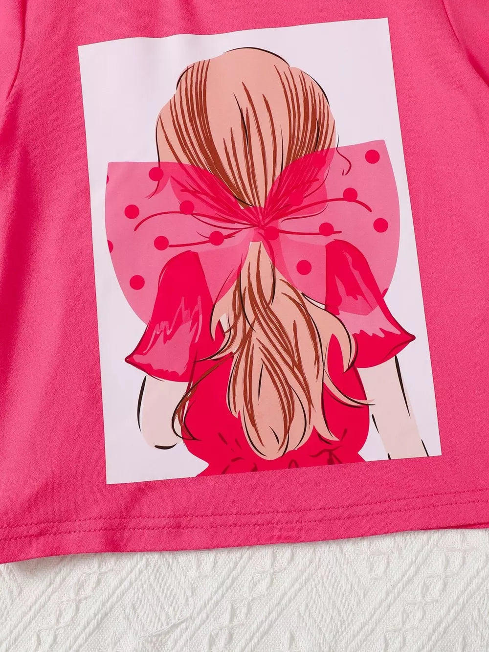 Pink tee with graphic of girl with polka dot bow and ruffled dress.